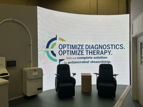 Painel de LED curvo integrado a estande em congresso de hospitais, com poltronas e conteúdo da marca